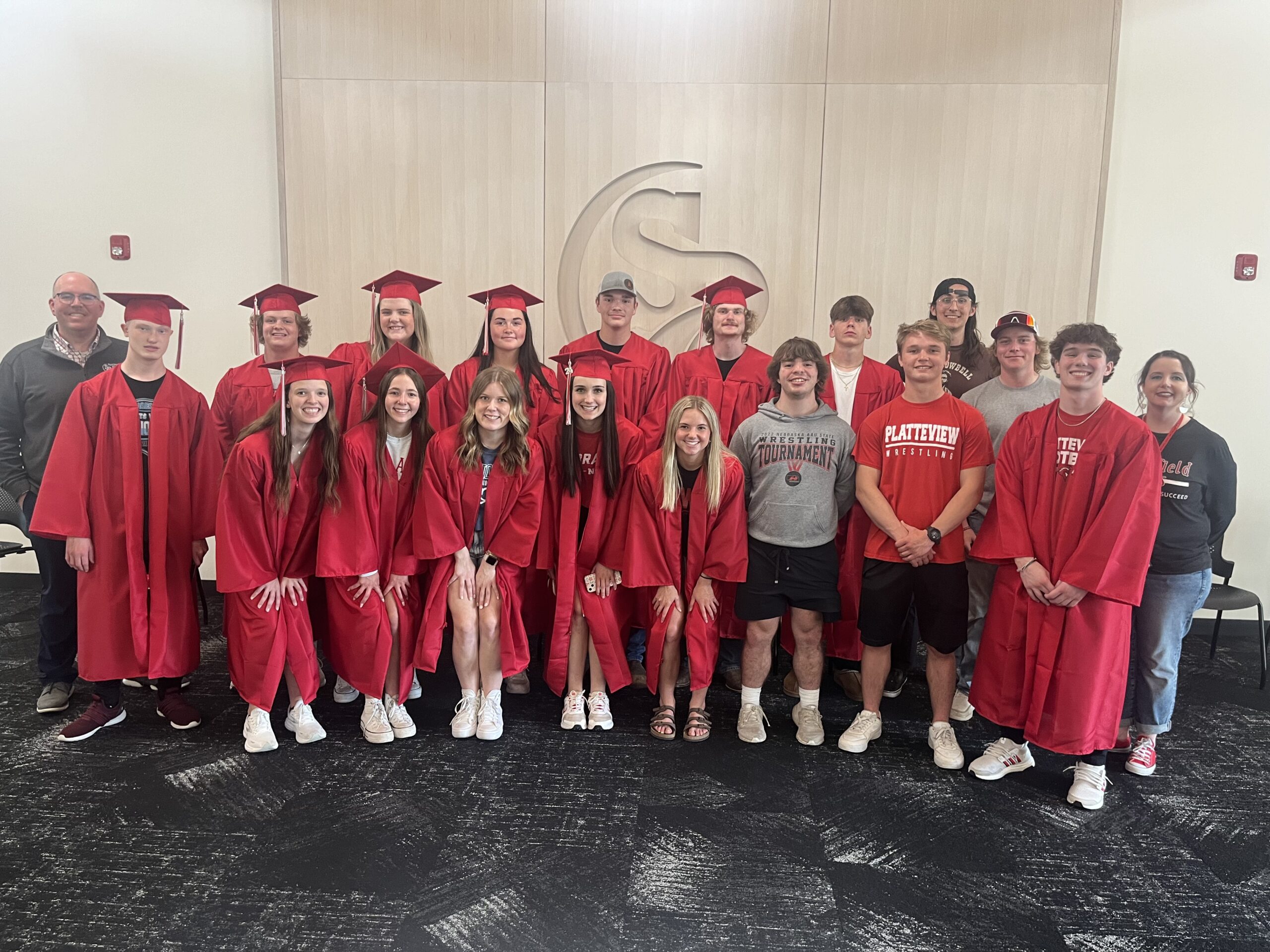 many students gathered at the administration building, taking a group picture in their cats and gowns in the Board of Education room with the Springfield elementary principal and the superintendent of schools