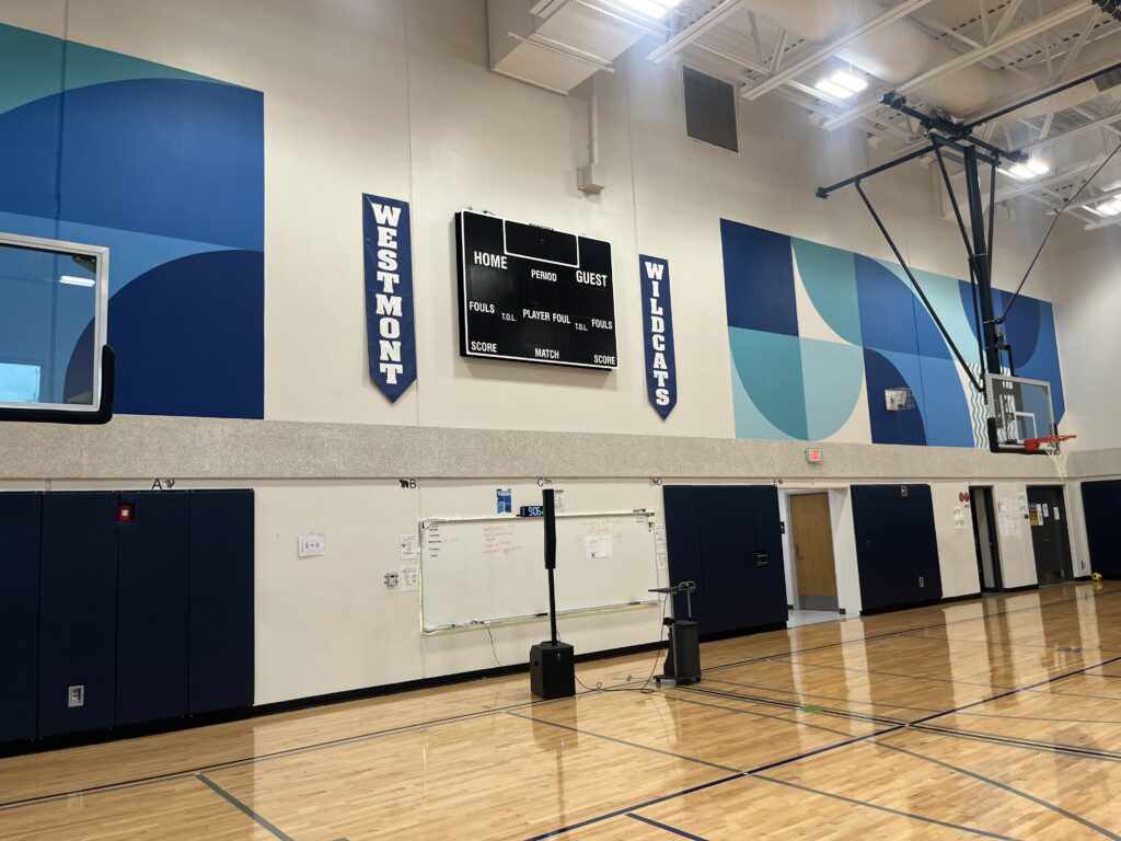 Westmont Elementary School gym picture with a blank sports score board on the wall and colors of blue